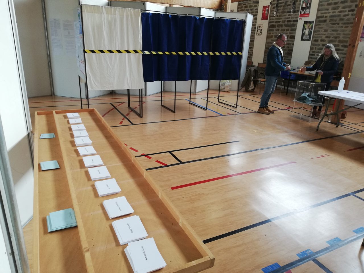 Bureau de vote français avec urne transparente et isoloirs, lieu où les citoyens votent lors d'un référendum ou d'une élection en France