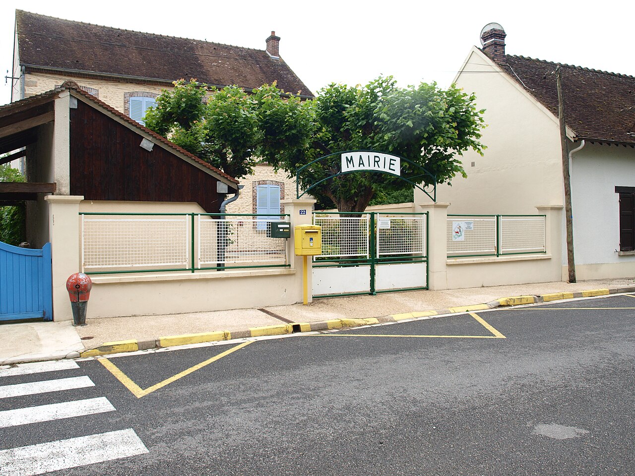 Façade d'une mairie de village français avec le drapeau tricolore, symbole de la commune, plus petite collectivité territoriale de France